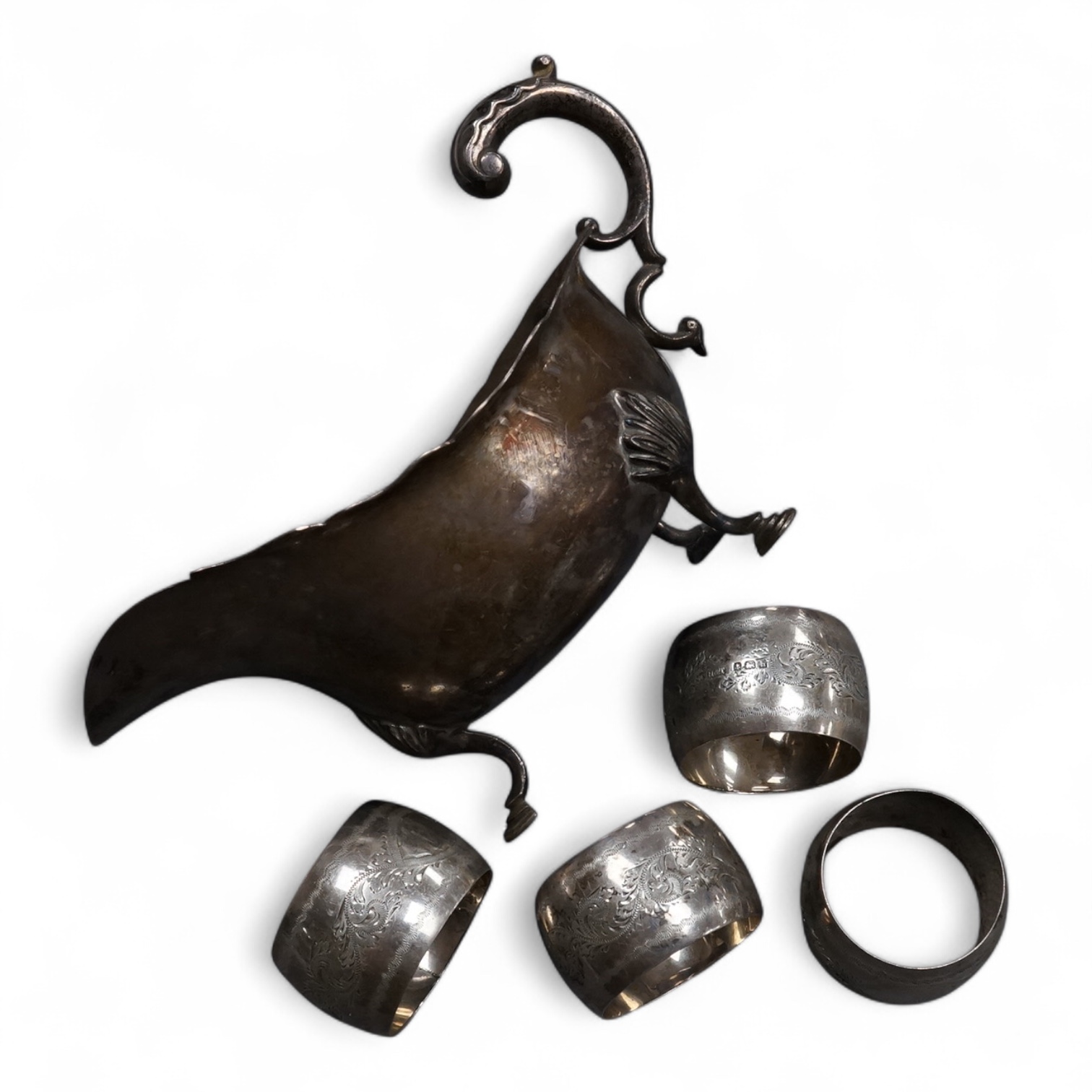A George V silver sauceboat, with flying scroll handle, Jay, Richard Attenborough Co Ltd, Sheffield, 1925, together with a set of four Edwardian silver napkin rings, 11.3oz.